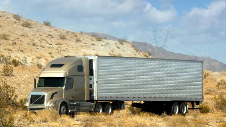 Beige semi-truck in a desert, showcasing Yes2Qatar's road freight services between Iraq and Qatar for cargo transport.